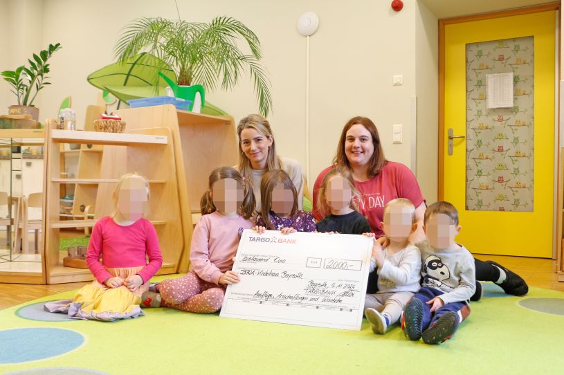Vanessa Grüner (stv. Leitung der Targobank Bayreuth, links), bei der Übergabe der Spende in Höhe von 2.000 Euro an das BRK-Kinderhaus (vertreten durch Kathrin Friedrich Leitung der Gruppe „Knallerbsen“ des BRK-Kinderhauses) mit Kindern des BRK-Kinderhauses. Foto: Tobias Schif /BRK